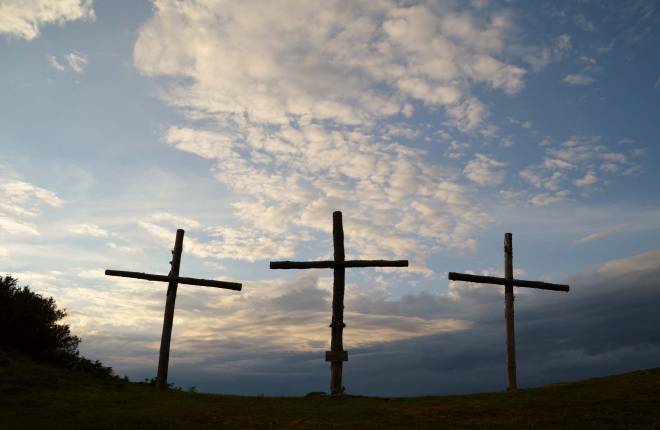 Three crosses on hill with sky behind
