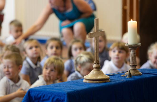 primary school children in background, altar with cross in foreground 
