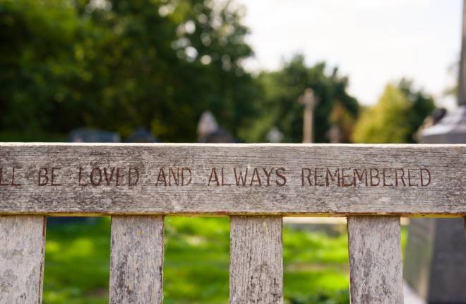 Focus on the words Loved and always remembered carved on a memorial bench