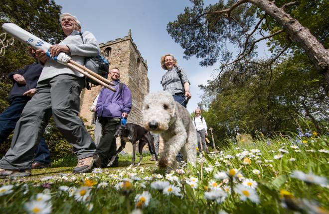 Vicar and parishioners with dogs walk past church on prayer walk