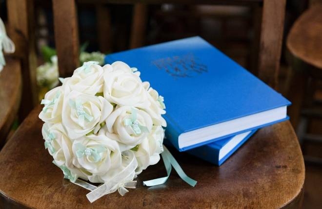 Blue hymn books and a bouquet resting on a chair